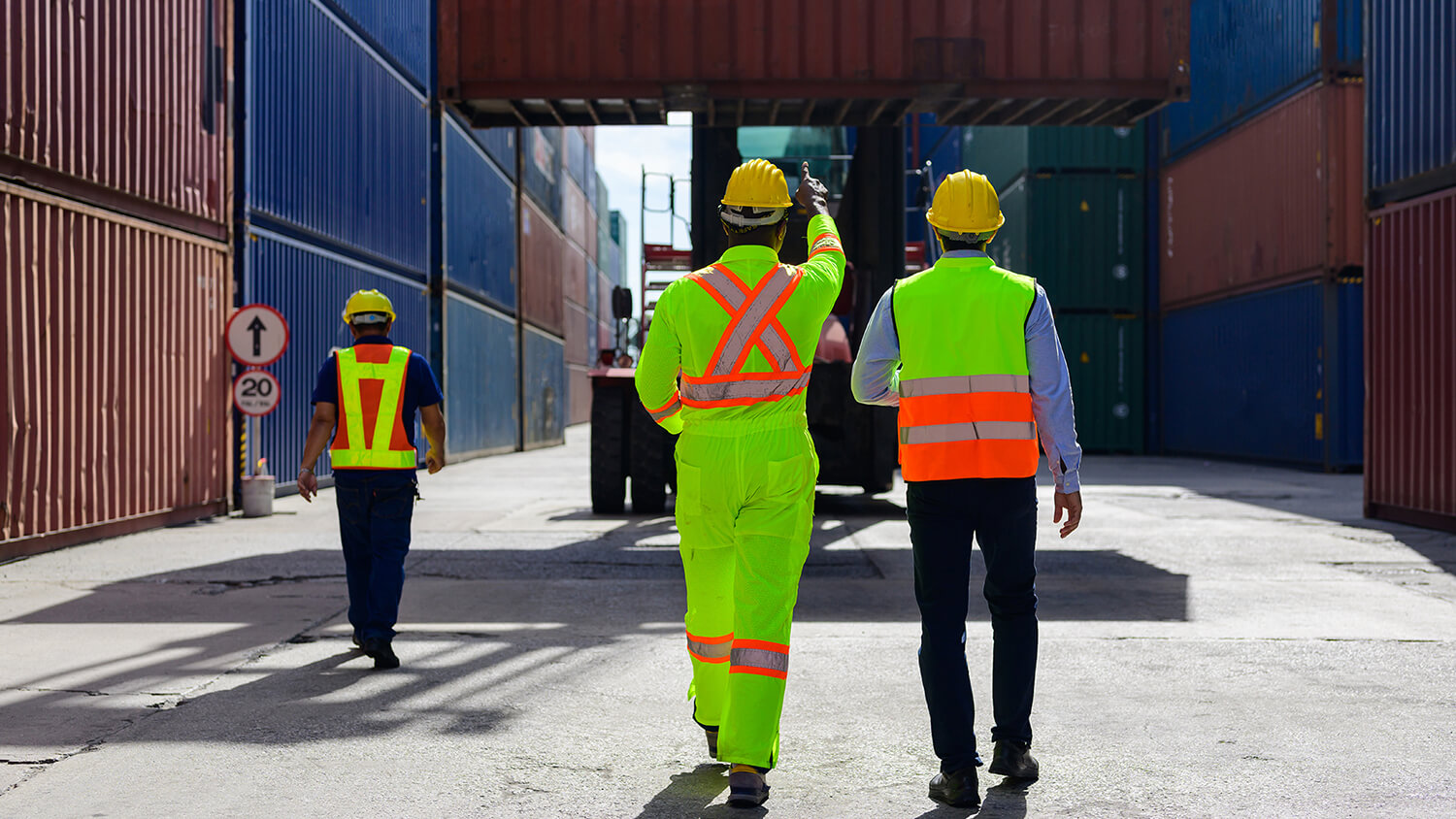 Trabajadores en centro logístico caminando hacia una grúa